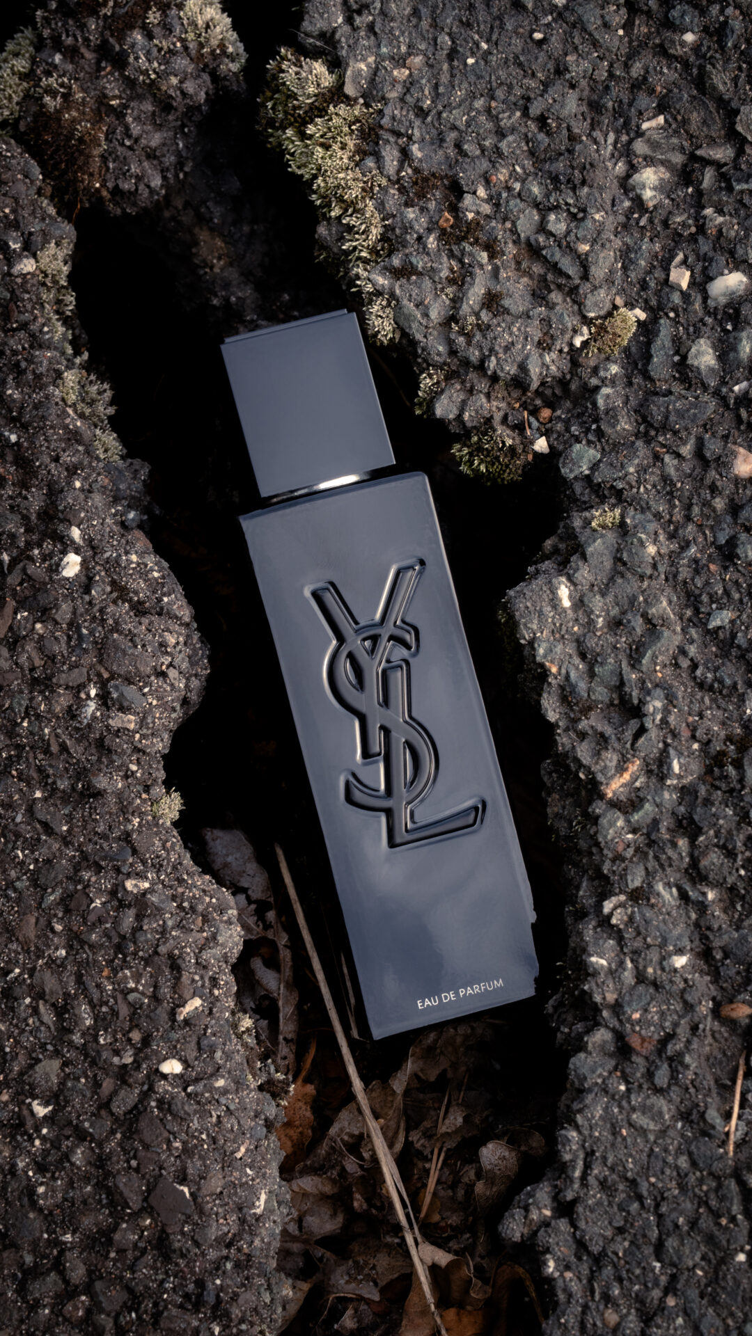 Parfüm von Yves Saint Laurent zwischen zwei Straßenplatten